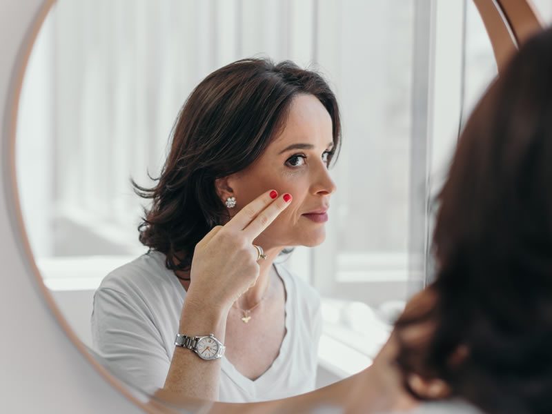 Dr. Débora Cadore em frente ao espelho conferindo sua pele do rosto. Cuidados diarios com a pele